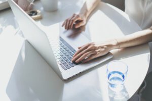 Beautiful woman working on a laptop sitting at the table in living room of modern house